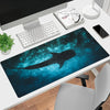 A dark blue and black whale shark design mouse pad with an anti-slip rubber base on a white desk.