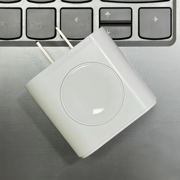 A white 3-in-1 multi-port fast charger device resting on a gray laptop keyboard.