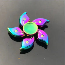 A collection of iridescent, rainbow-colored metal fidget spinners shaped like leaves and petals.
