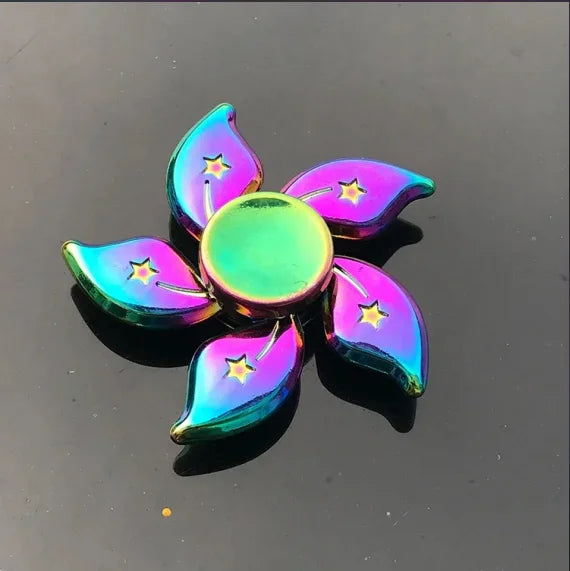 A collection of iridescent, rainbow-colored metal fidget spinners shaped like leaves and petals.