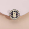 An enamel pin featuring a ghost surrounded by butterflies with the text Living the Dream One Nightmare at a Time