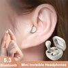 A hand holds a white mini invisible headphone device next to a person's ear, showing the product design.