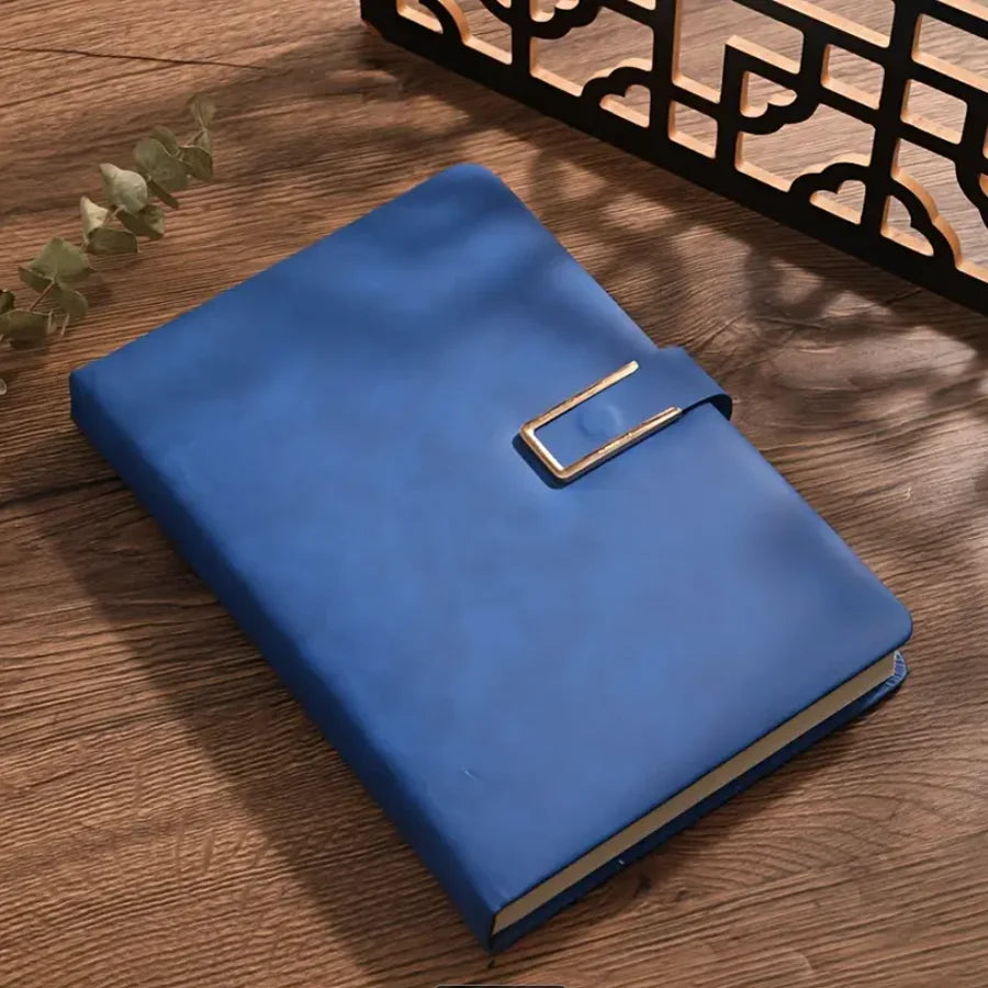 A blue A5 retro leather notebook with a gold-toned clasp resting on a wooden surface.