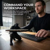 A man is working at a desk with a matte black ninja figurine pen holder on the wooden surface.