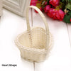 A light beige heart-shaped woven basket made of natural rattan with a handle.
