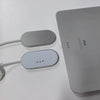 A silver magnetic wireless charging adapter and cable next to an iPad.
