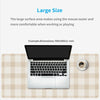 A silver laptop is placed on a beige plaid mouse pad with a coffee cup nearby.