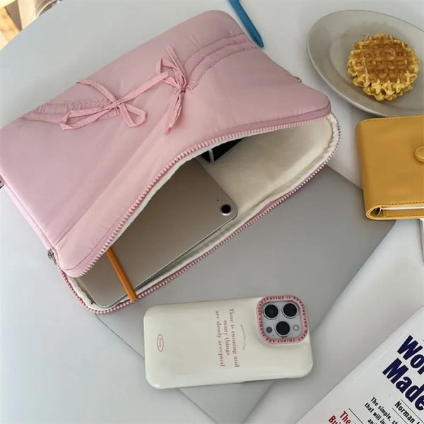 A pink ultra-thin laptop sleeve case is shown open, revealing a padded interior and a yellow waffle snack nearby.