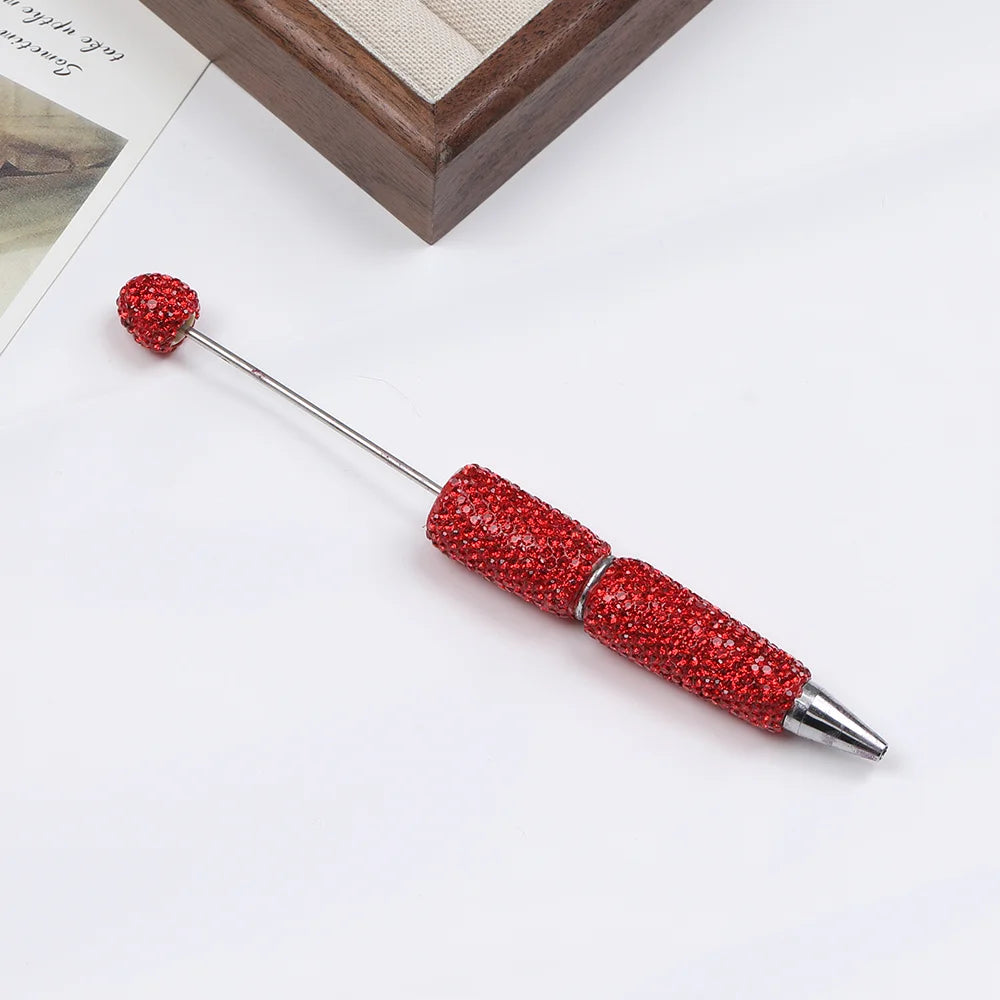 A silver pen accessory with a red rhinestone ball and a sparkly red body is shown on a white background.