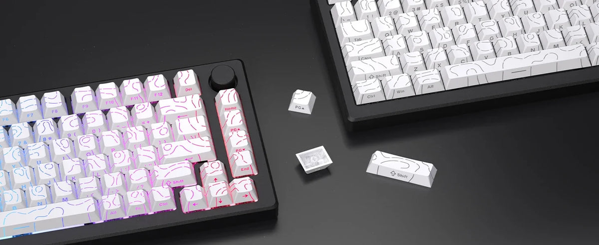 A close-up view of a black mechanical keyboard and various white and pink PBT keycaps and legends scattered on a dark surface