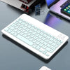 Eine weiße Mini-kabellose Bluetooth-Tastatur auf einer grauen Oberfläche neben einem Laptop.