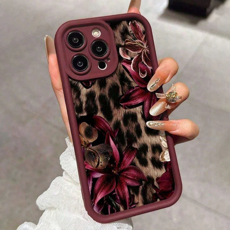 A hand holds a dark mauve leopard print phone case featuring deep purple floral designs.