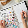 A hand is writing in an expense tracker section of a monthly budget planner with various spending categories and income detai