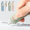 A hand holds a light green portable mini paper cutter with multiple color options, demonstrating its compact design.