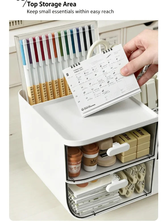 A white desk organizer with two clear storage drawers holds pens and a paper list.