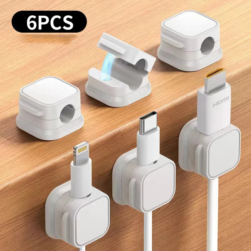 A set of six white magnetic cable clips and charging adapters are displayed on a wooden surface.