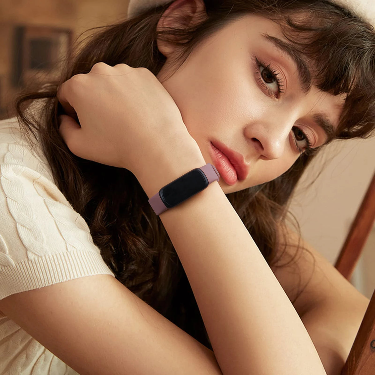 A close-up of a woman wearing a dark silicone replacement strap on her wrist.