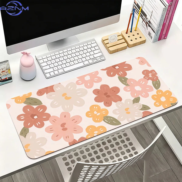 A pink floral mouse pad with orange accents is displayed on a white desk next to a computer monitor and stationery.
