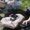 A hand is using a portable solar power bank charger to wirelessly charge a smartphone outdoors on a rock.