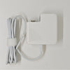 A white universal laptop charger with a cord is mounted on a wall.