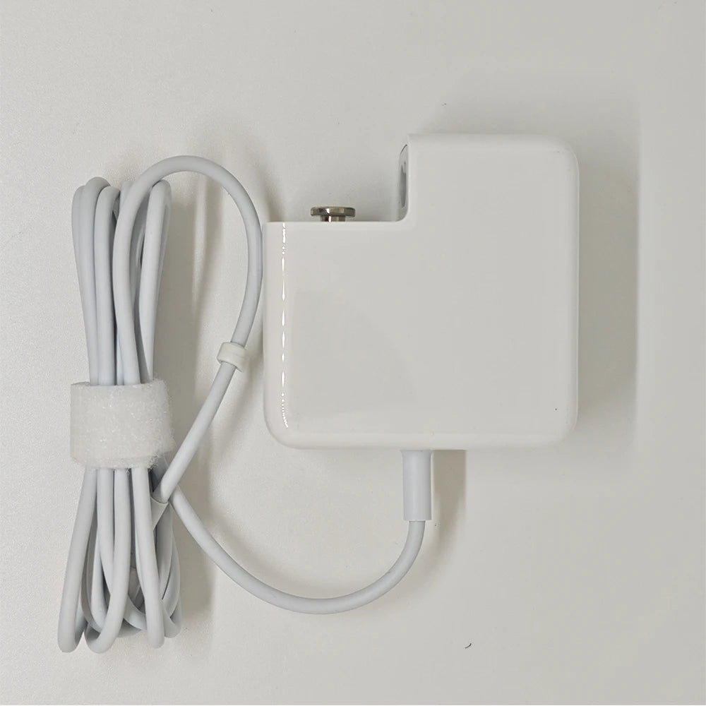 A white universal laptop charger with a cord is mounted on a wall.