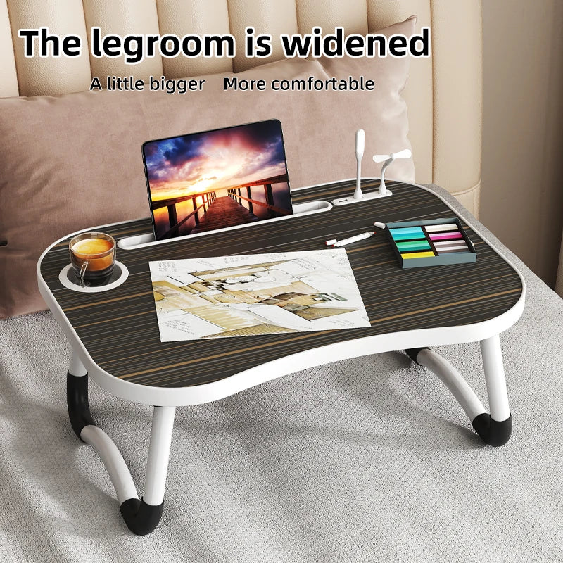 A laptop desk organizer tray with a wooden surface holding a laptop, pens, and a color pencil set on a light-colored table.