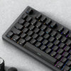 A close-up view of a black mechanical keyboard with PBT double-shot cherry profile keycaps and a wrist rest.