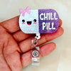 A sparkly purple and white badge reel holder shaped like a cloud with a pink bow and the text CHILL PILL