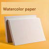 A stack of white watercolor paper pads is displayed on a yellow background.