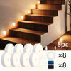 Set of eight motion sensor LED night lights and eight black mounting plates for cabinet lighting.