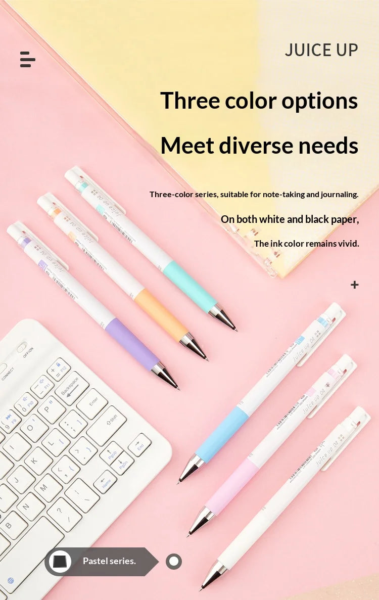 A set of three colored Pilot Juice Up fine point gel pens displayed on a pink background with a white laptop visible.