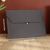 A gray leather document organizer bag with a flap closure shown against a wooden background.