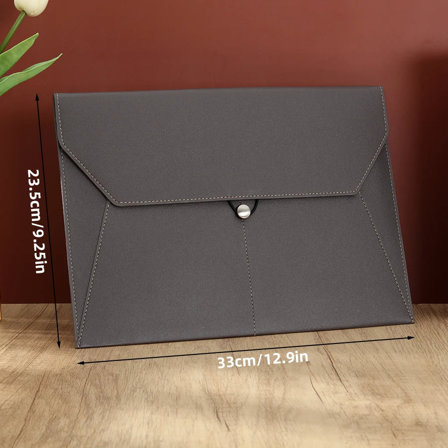 A gray leather document organizer bag with a flap closure shown against a wooden background.