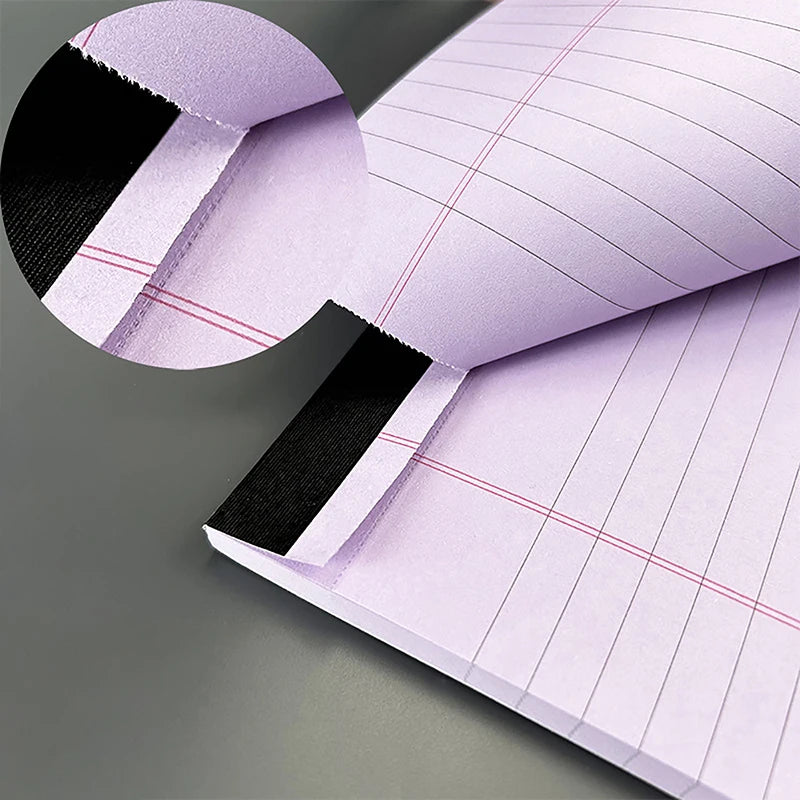 A close-up of a tearable lined writing pad in light purple with black accents, shown open and partially folded.