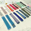 A collection of colorful nylon loop watch straps in various colors and patterns laid out on a white surface.