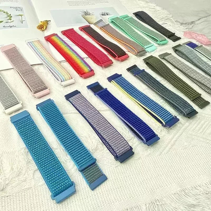 A collection of colorful nylon loop watch straps in various colors and patterns laid out on a white surface.