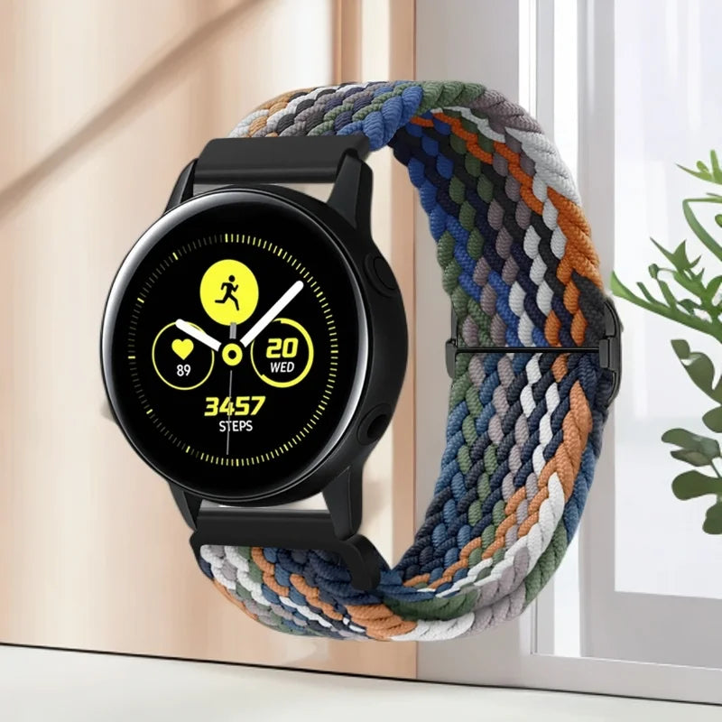 A black smartwatch with a colorful nylon watch strap is displayed against a light background.