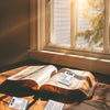 Eine offene Bibel liegt auf einer Holzoberfläche neben mehreren Karten mit inspirierenden Glaubensversen.