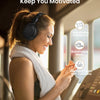 A woman wearing a gray knitted headband and headphones is smiling while using fitness equipment.