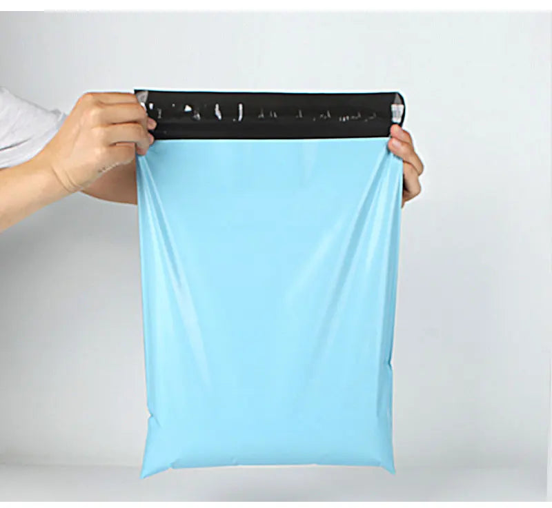 A hand is holding a light blue reusable waterproof poly shipping bag with a black measuring tape on top.