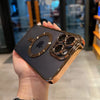 A hand holds a dark phone case with a gold plated finish and a clear magnetic back for a MagSafe iPhone.