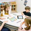 Three children are gathered around a large chart with colored markers and grids for behavior tracking.