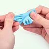 A hand holds a light blue silicone pencil grip writing corrector for children.