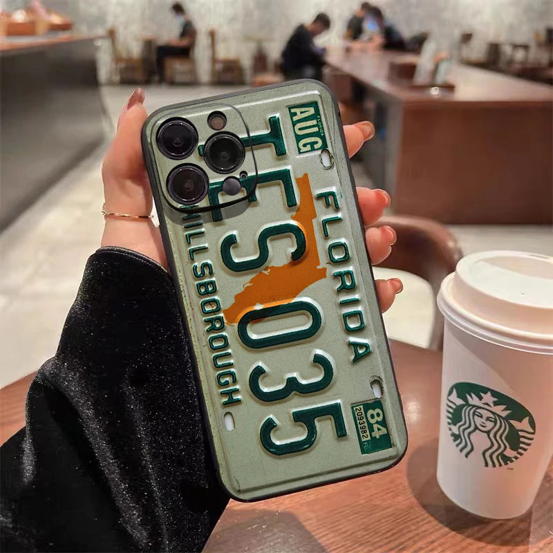 A hand holds a vintage license plate phone case for an iPhone featuring the Florida state design.