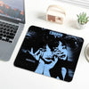 A black mouse pad featuring a blue and black graphic of Tomie from Junji Ito, with stitched edges, placed next to a laptop an