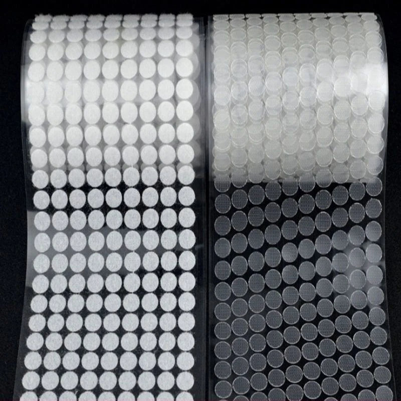 Roll of white self-adhesive hook and loop fasteners with circular adhesive pads.