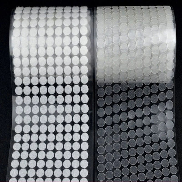 Roll of white self-adhesive hook and loop fasteners with circular adhesive pads.