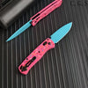 A pink acrylic folding knife with a light blue blade is shown on a dark surface.