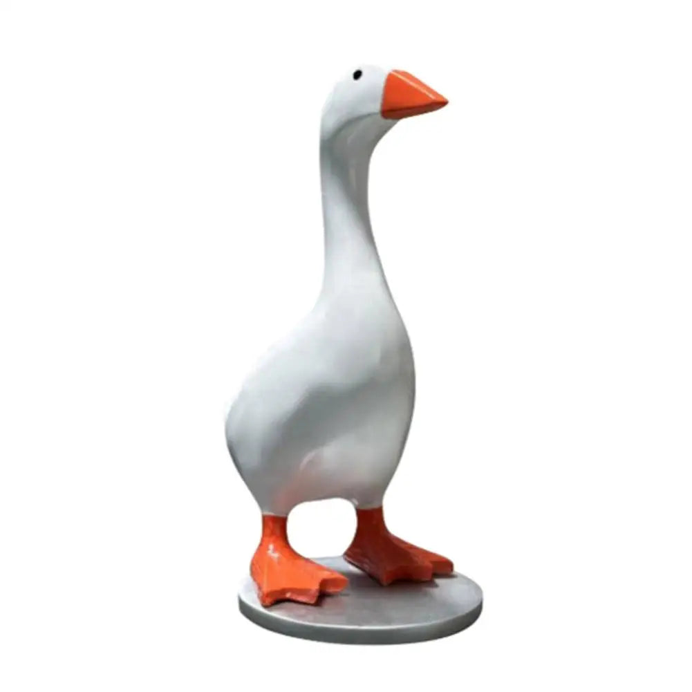 A white resin duck figurine with an orange beak and feet, standing on a gray base.