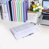 A set of colorful A4 document and photo storage file boxes lined up next to a laptop and a box of flowers.